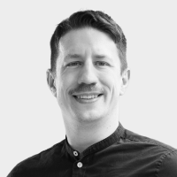 Black and white portrait of Bernhard Kratzwald smiling in a button-up shirt