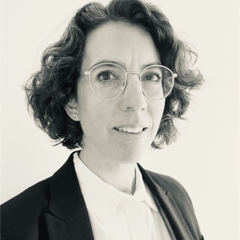 Black and white portrait photo of Jessica Valli wearing glasses and a dark blazer